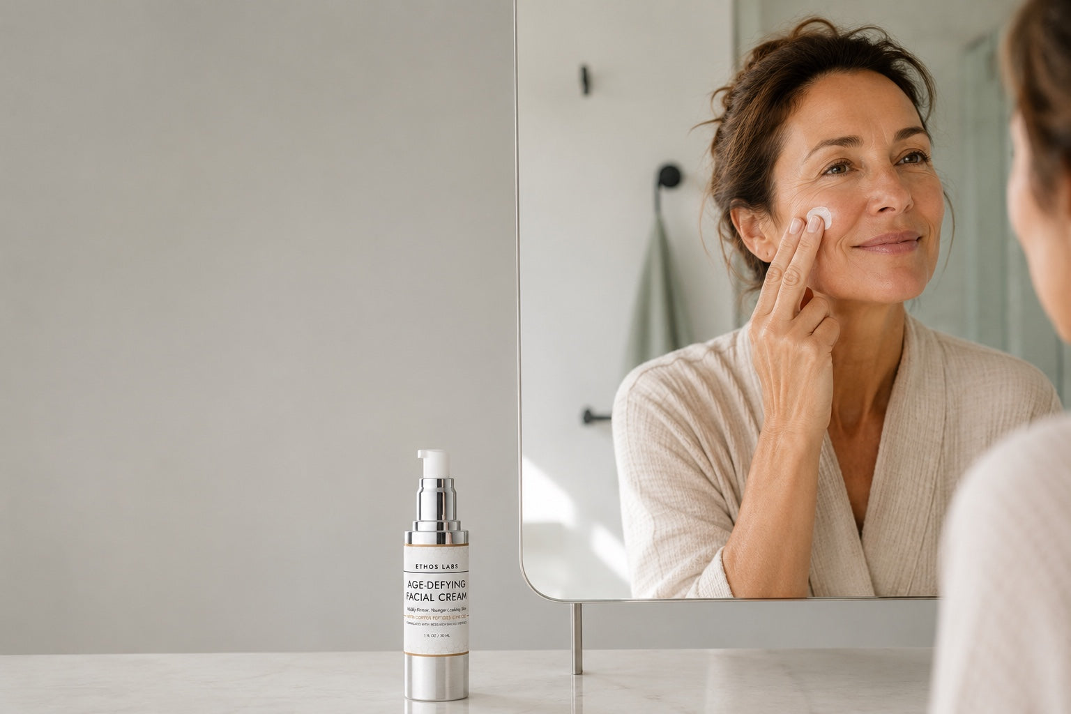 A woman applying Ethos Labs Age-Defying Facial Cream at her bathroom mirror as a one-step morning routine